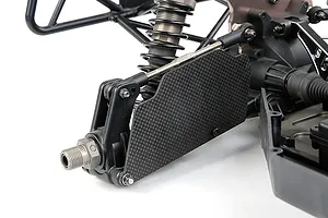 Carbon fibre rear suspension arm guard installed on an RC car chassis, showing the weave pattern and mounting hardware.