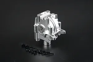 A silver Rovan aluminium gearbox case for an RC car, shown with a set of black mounting screws on a dark background.