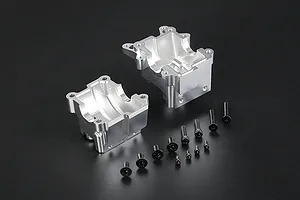 Silver aluminium RC gearbox case halves with a set of black mounting screws on a dark background.