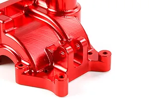 A close-up view of a red anodized aluminium gearbox case for an RC car, showing machined details and mounting points.