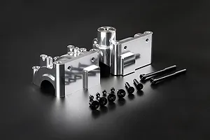 Silver Rovan aluminium gearbox case set with included screws and ball bearing on a black background.