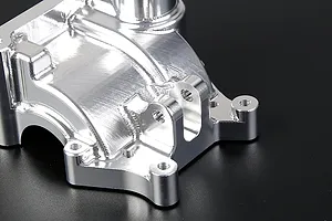 A close-up view of a silver Rovan aluminium gearbox case showing machined metal surfaces and mounting points.