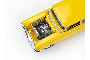 High-angle view of a yellow 1957 Chevrolet Bel Air model car with the hood open, revealing a detailed chrome engine bay.