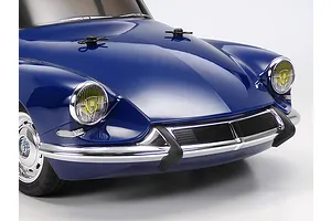 Close-up of the front end of a blue Tamiya Citroen DS RC car model, showing the hood, chrome bumper, and yellow-tinted headlights.