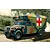 An illustration of an M997 Humvee Maxi Ambulance driving on a dirt road with a camouflage paint scheme and red cross markings.