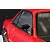 A close-up of a black racing-style door mirror mounted on the red body shell of a 1/10 scale RC car.
