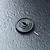 A black MST 50T spur gear with a small metal pin resting on a textured dark grey surface.