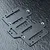 A black FRP battery mounting plate for an RC car, featuring multiple cutouts and countersunk mounting holes, set against a textured dark background.