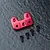 A red anodized aluminium steering arm mount for an RC car, accompanied by four black flat-head screws on a dark textured surface.