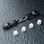 A black MST aluminium adjustable lower suspension arm mount with four small white plastic inserts on a dark textured surface.