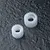 Two white plastic idler gears of different sizes resting on a dark textured surface.