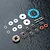 A set of MST limited slip differential parts including metal gears, washers, pins, O-rings, and a blue gasket on a dark textured surface.