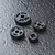 A set of four grey plastic RC drive gears of varying sizes arranged on a dark textured surface.