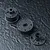Three black plastic RC gearbox components arranged on a textured dark grey surface.