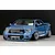 Blue Toyota Tundra RC truck body shell mounted on an RC chassis with wide fenders and custom wheels against a dark background.