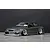 Studio product shot of a grey ER34 Skyline 4-door RC drift car body shell mounted on a chassis with custom wheels against a dark grey background.