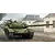 An artistic illustration of a Russian T-72A main battle tank moving down a dusty road past damaged buildings.