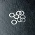 A small pile of eight thin, silver-coloured metal washers resting on a black textured surface.