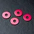 Four small, circular, red anodized metal wheel hub spacers arranged on a black textured surface.