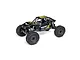 Axial UTB10 Capra 1.9 4WS RC rock crawler in yellow and black, featuring a tube chassis, large off-road tires, and detailed driver figure.