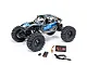 Axial UTB18 Capra 4WS RC rock crawler in blue and grey, shown with included Spektrum battery, USB charger, and cable on a white background.