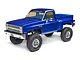 Axial SCX10 III Base Camp 1/10 scale RC rock crawler featuring a blue 1982 Chevrolet K10 pickup truck body on a white background.