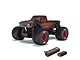 ARRMA Quake Grom 1/16 scale RC monster truck in red and black, shown with a Spektrum Smart G2 LiPo battery and charger on a white background.