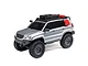 A silver Axial SCX24 Lexus GX 470 RC rock crawler with a roof rack, off-road accessories, and black wheels against a white background.