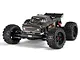 Studio shot of the ARRMA Outcast 4X4 BLX 4S RC stunt truck in gunmetal grey, featuring large off-road tires and a detailed pickup truck body.
