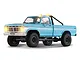 Studio product shot of the FMS FCX18 II Ford F-100 RC Rock Crawler in cerulean blue with working lights lit against a white background.