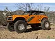 An orange Axial Wraith 1.9 RC rock racer truck parked on a dirt trail in an outdoor desert environment.