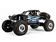 Axial RR10 Bomber 2.0 1/10 scale RC rock racer in blue, featuring a tubular roll cage, off-road tires, and detailed driver figures.