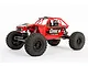 A red Axial Capra 1.9 4WS RC rock crawler buggy on a white background, featuring a tube chassis, off-road tires, and detailed driver figures.