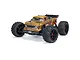 ARRMA Outcast 4S BLX stunt truck in bronze finish, featuring large off-road tires, a rear wing, and detailed body decals on a white background.