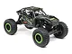 Axial UTB18 Capra 1/18 scale RC rock crawler in black with green accents, featuring a tube chassis, off-road tires, and driver figures.