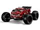 A studio shot of the red ARRMA Outcast 4X4 BLX 4S RC stunt truck, featuring large off-road tires and a detailed truck body.