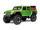 A studio shot of the Axial SCX24 Jeep Gladiator RC rock crawler in green, featuring black wheels with green trim and a red accessory mounted in the truck bed.