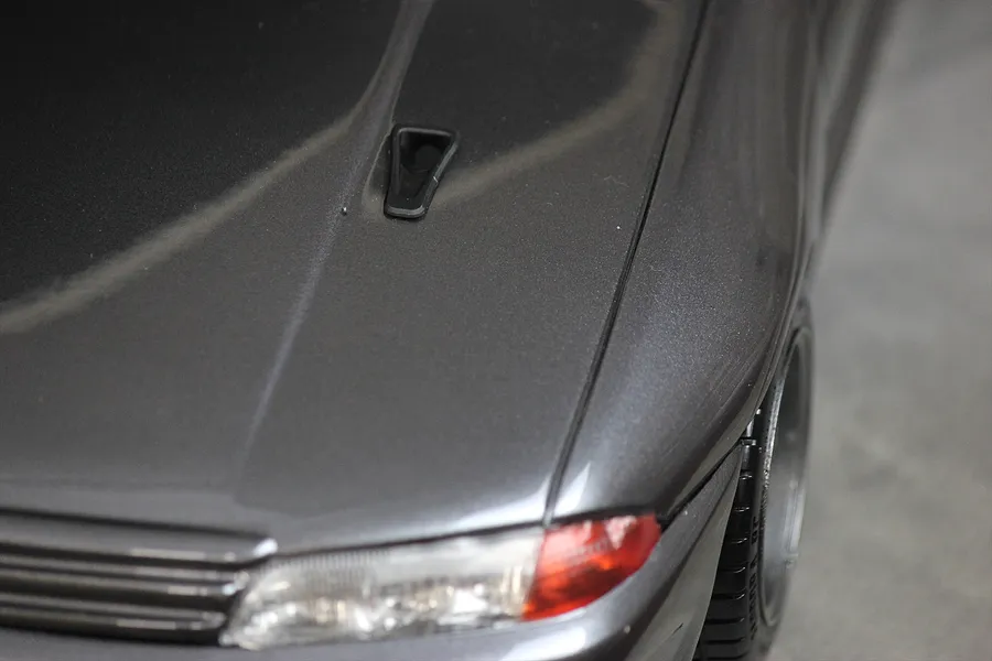Close-up of a dark grey RC car hood featuring a black NACA duct installed on the surface.
