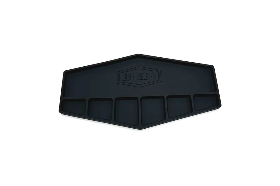 A black silicone parts tray by Reefs RC with a shield-shaped design and multiple compartments for organizing small hardware.