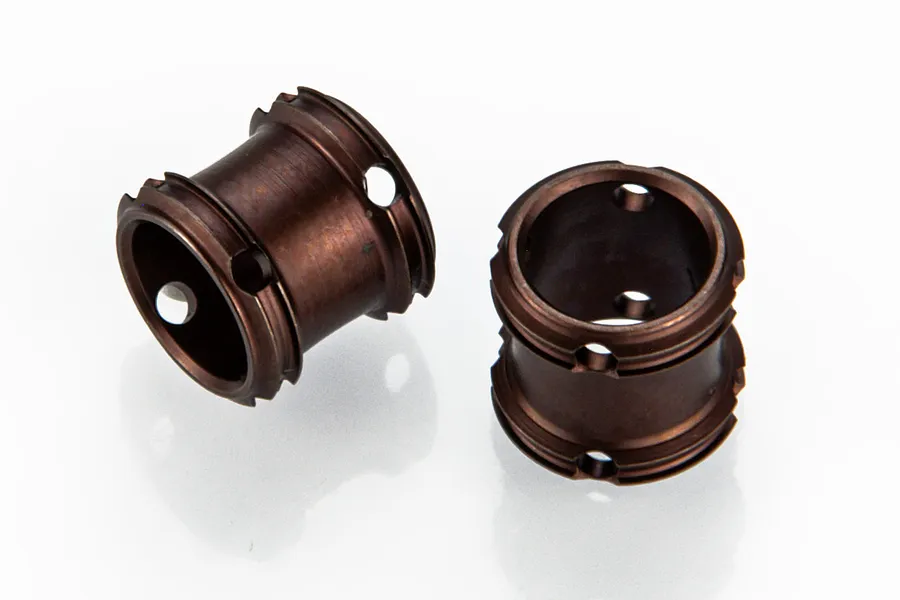 Two dark bronze-coloured cylindrical RC driveshaft couplings with small holes, isolated on a white background.