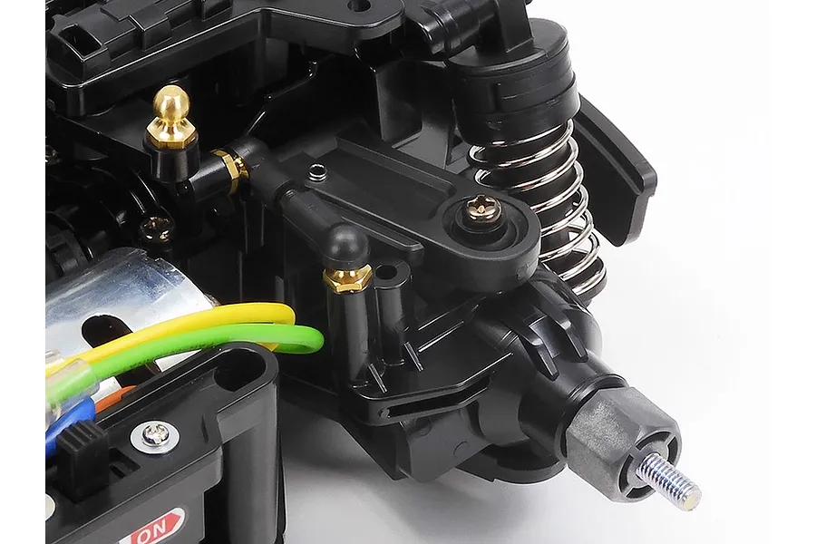 Close-up of the front suspension and steering assembly of a Tamiya MB-01 RC car chassis.