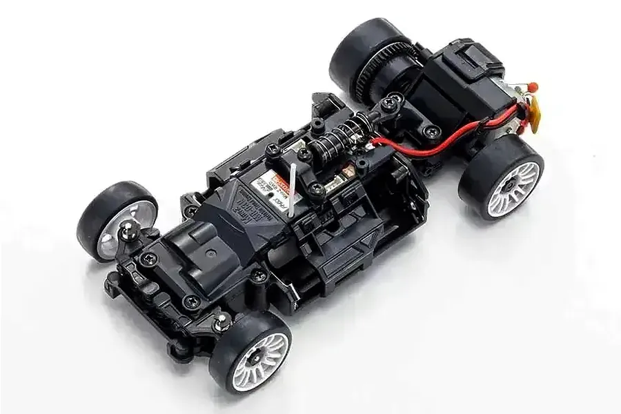 Top-down view of a Kyosho Mini-Z RC car chassis without the body shell, showing the black plastic frame, wheels, and internal components.