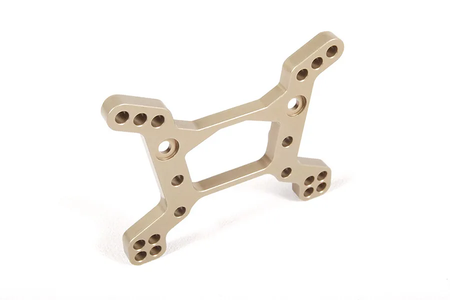 A gold-anodized aluminium front shock tower for an RC vehicle, featuring multiple mounting holes for suspension adjustment.