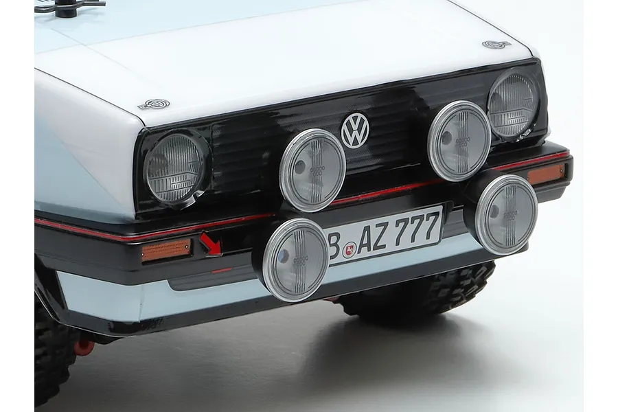 Close-up of the front end of a Tamiya Volkswagen Golf MK2 GTI RC rally car, showing the headlights, rally spotlights, and grille.