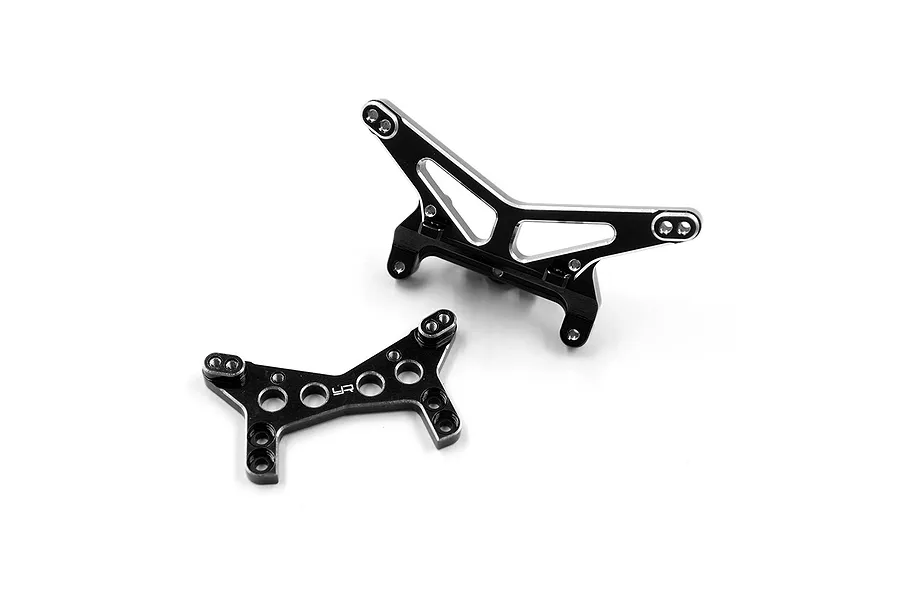 Two black anodized aluminium RC shock towers from Yeah Racing, featuring silver chamfered edges and multiple mounting holes.