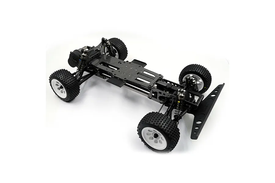 A high-angle studio shot of an assembled RC car chassis featuring a carbon fiber deck, black plastic components, and white wheels with off-road tires.
