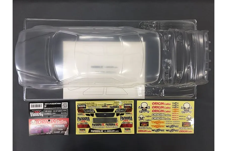 Unpainted clear polycarbonate RC body shell of a Toyota Chaser JZX100 with included decal sheets and instruction card on a dark background.