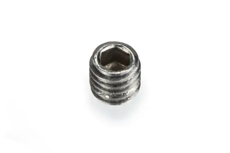 A single small metal grub screw with a hexagonal socket drive, shown from an angled top-down perspective against a white background.