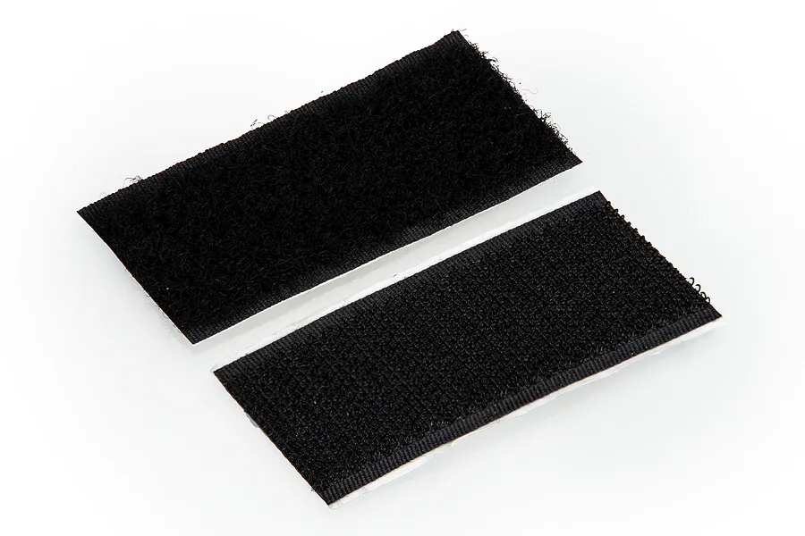 Two rectangular strips of black adhesive-backed hook and loop fastener tape on a white background.