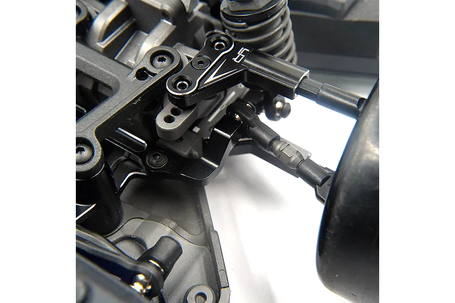 Close-up of a black aluminium Yeah Racing suspension arm installed on an RC car chassis.